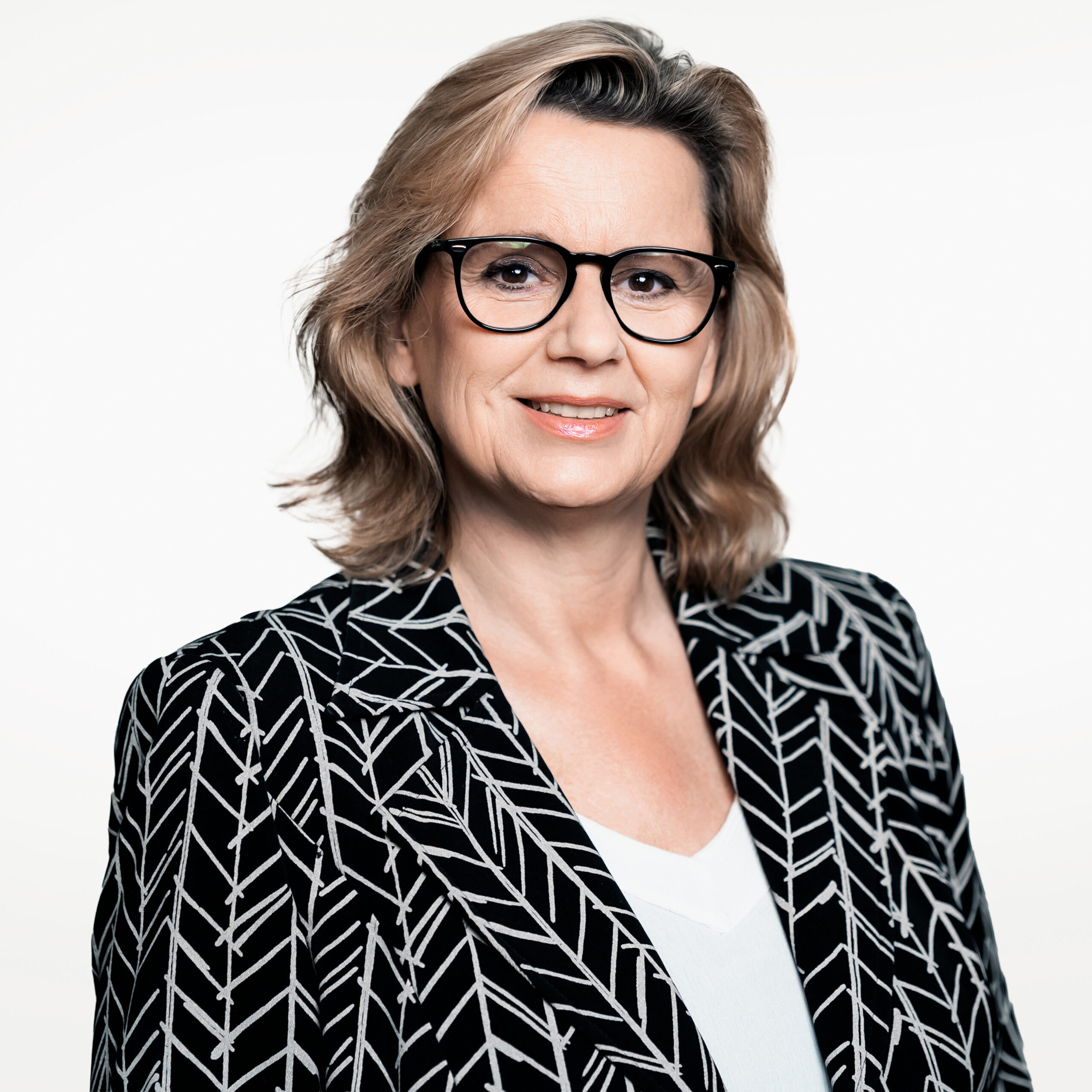 Diana Post, professionelle Fotografin aus Berlin, mit stilvollem Auftritt im grafisch gemusterten Blazer – spezialisiert auf hochwertige Porträt-, Casting-Akt- und Fine-Art-Fotografie.